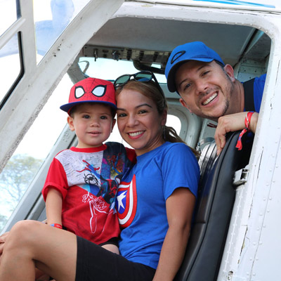 man woman and child in landed helicopter posing for picture wearing superhero t-shirts
