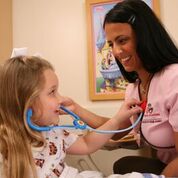 Child playing with toy stethoscope on nurse