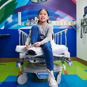Girl smiling while tying shoe in pediatric emergency room